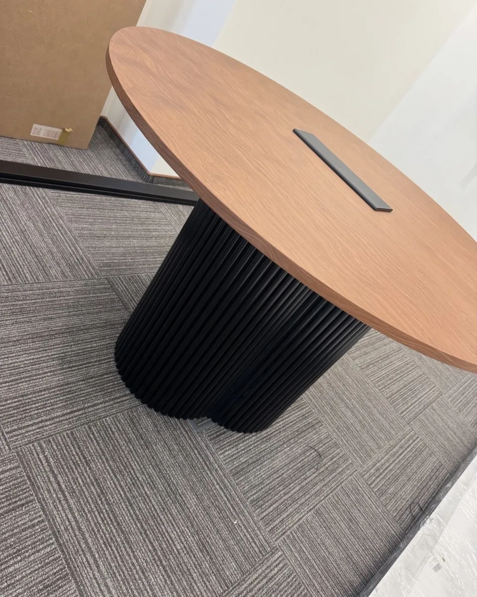 Round conference table with a wooden top on a black fluted base