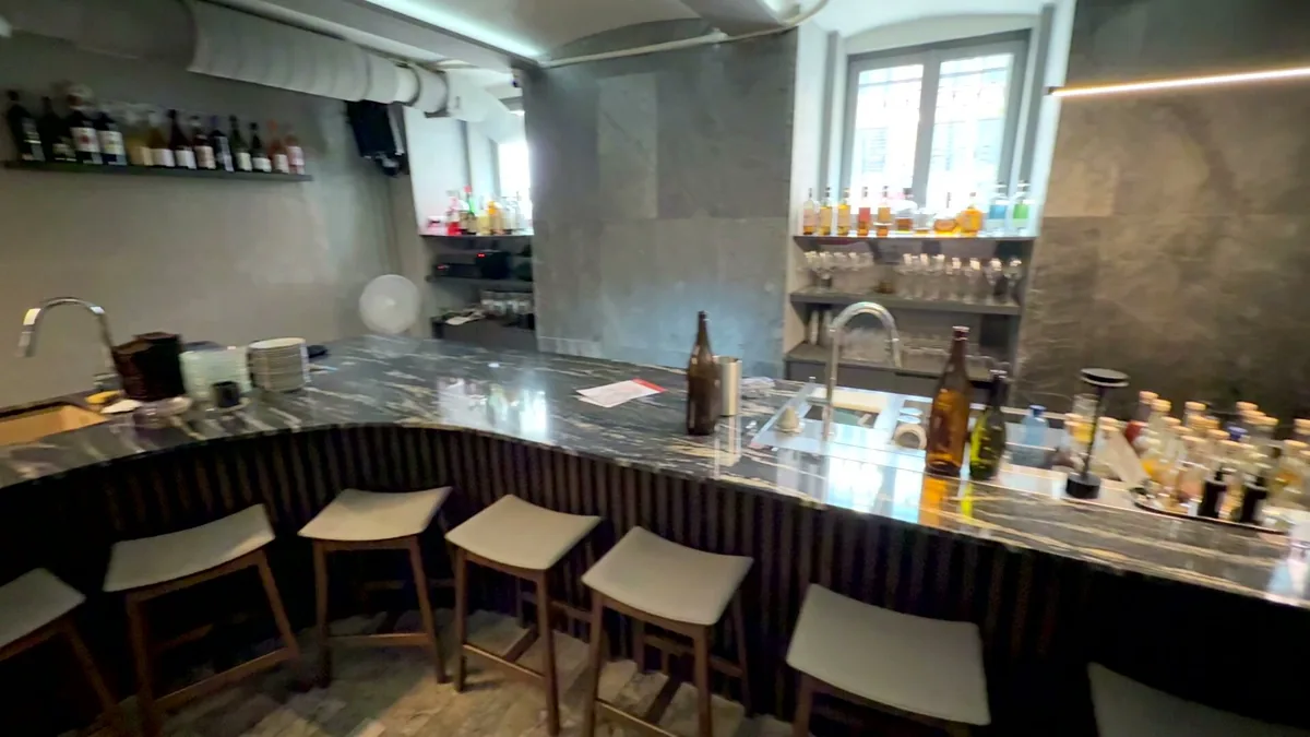 Барная стойка дугой через зал ресторана IKI izakaya: мойка и рабочая столешница со стороны бармена, табуреты для гостей